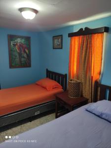 two beds in a room with blue and orange walls at HotelCasaMorazanGranadaNicaragua in Granada