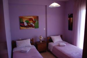 2 letti in una camera con pareti viola di Nikos Apartments a Ioannina