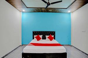 a bed with red pillows in a blue room at The Cawnpore Inn in Kānpur