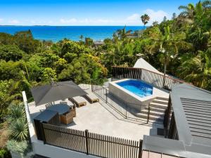 an aerial view of a house with a swimming pool and the ocean at Moonrise in Byron Bay