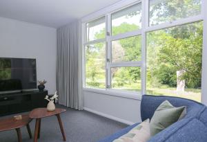 a living room with a blue couch and a large window at Tree View Cottage in Wandiligong