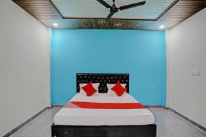 a bed with red pillows in a blue room at The Cawnpore Inn in Kānpur
