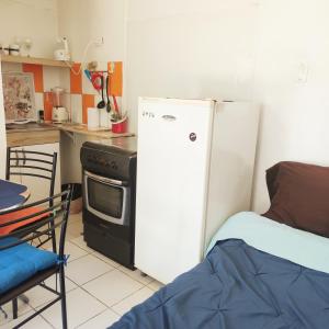 a kitchen with a refrigerator and a stove and a bed at Cabaña Playera cómoda y central in Viña del Mar