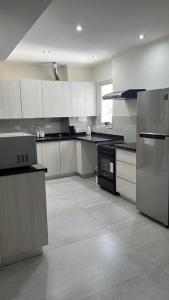 a large kitchen with white cabinets and stainless steel appliances at Departamento General Paz in Villa María +1 photo