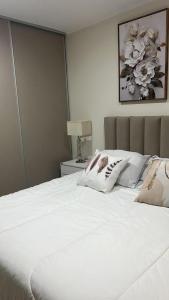 a bed with white sheets and pillows in a bedroom at Departamento General Paz in Villa María