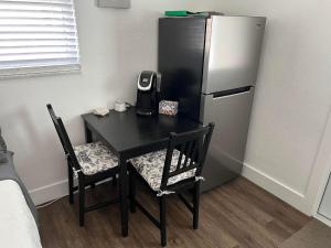 a black table with two chairs and a refrigerator at Cozy private studio w/own yard - 3mi from Beach in Seminole