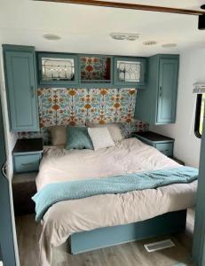 a bed in a small room with blue cabinets at Happy Camper - Close to Mackinac Island in Carp Lake