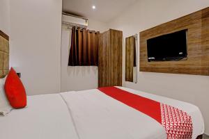 a bedroom with a bed with a tv on the wall at OYO Hotel Kishan in Mumbai