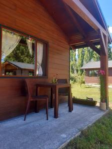 a wooden house with a table and a chair at Cabañas Alma del Sur in El Hoyo