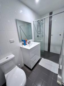 a white bathroom with a toilet and a shower at Entire 3 bed apartment in Ryde in Sydney