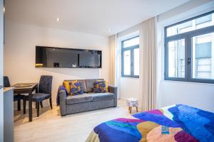 een slaapkamer met een bank, een stoel en een tafel bij Porto Formosa Central Lofts in Porto