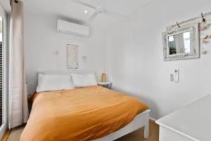 1 dormitorio blanco con 1 cama con sábanas de color naranja en The Waterfront House - Pet Friendly - Absolute Waterfront, en Erowal Bay