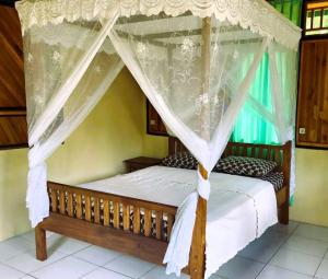 1 dormitorio con cama con dosel y cortinas blancas en Bunaken Sea Garden Resort, en Bunaken