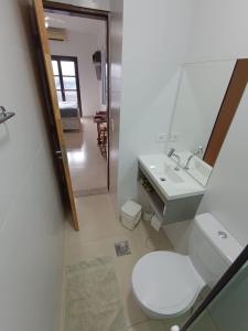 La salle de bains est pourvue de toilettes, d'un lavabo et d'un miroir. dans l'établissement Flat Maresias 50m da Praia - 02 Mar & Tur, à Maresias