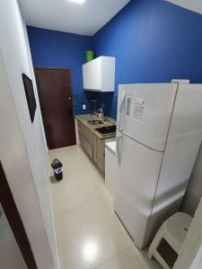 a kitchen with a white refrigerator and a blue wall at Flat Maresias 50m da Praia - 02 Mar & Tur in Maresias