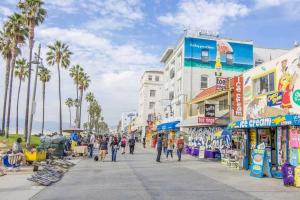 a group of people walking down a street with palm trees at Venice Beach International Traveler Cabins - Surf & Yoga & E-Bike in Los Angeles