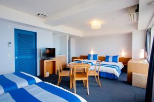 a hotel room with two beds and a table and chairs at The Beach Tower Okinawa in Chatan