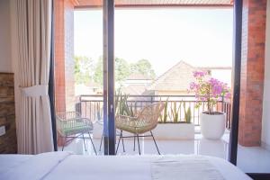 a bedroom with a bed and two chairs on a balcony at Cansa Seminyak in Seminyak