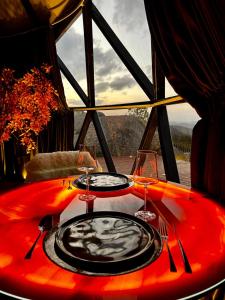 - une table rouge avec deux assiettes et des verres à vin dans l'établissement Monte dos Domos, à Gameleiras