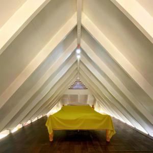 a bed in a tent with a yellow sheet at MOOREA - Fare Tiki Beach in Haapiti
