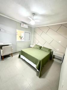 a bedroom with a green bed and a desk at Pousada Praia Grande in Ubatuba
