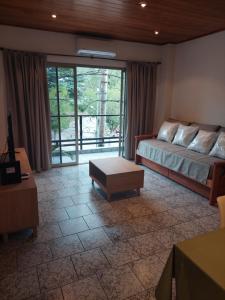 a living room with a bed and a large window at Departamento La Plaza in La Falda