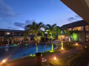 a pool at night with palm trees and buildings at Flat Village Imbassai in Imbassai