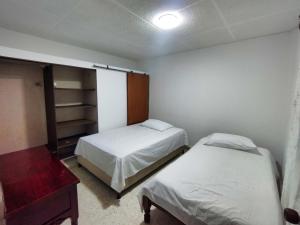 um quarto com 2 camas, uma cómoda e uma mesa em Hostal, casa Jaramillo em Roldanillo