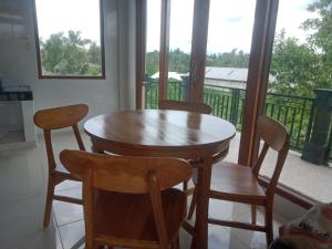 una mesa de madera y sillas en una habitación con balcón en Chiinta House, en Ubud