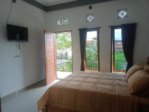 1 dormitorio con 1 cama, TV y ventanas en Chiinta House, en Ubud