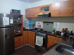 una cucina con piano cottura in acciaio inossidabile e mobili in legno di Bello y acogedora casa -departamento habitaciones a Lima
