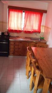 eine Küche mit einem Holztisch und einem roten Fenster in der Unterkunft ARROYO SERRANO-MINA CLAVERO in Mina Clavero + 20 Fotos