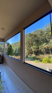 Habitación con 3 ventanas y vistas a los árboles. en Apartamento Vista Linda en Santa Teresa