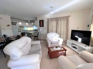 sala de estar con muebles blancos y TV de pantalla plana en Casa San Antonio en San Antonio de Arredondo