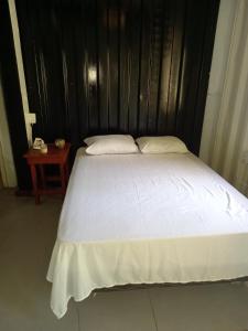 a white bed with a black headboard and a table at TOnat Caribe Hostel01 in West End