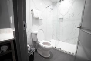 a white bathroom with a toilet and a shower at Palms Motel in Pico Rivera