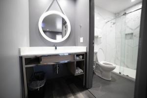 a bathroom with a sink and a mirror and a toilet at Palms Motel in Pico Rivera