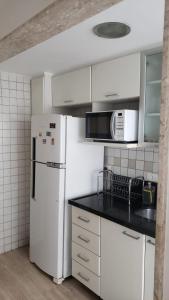 a kitchen with a white refrigerator and a microwave at Apartamento Frente Lagoa - RJ in Rio de Janeiro