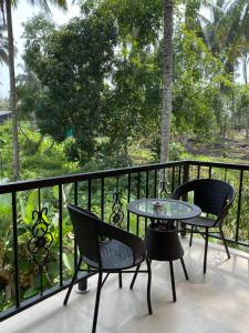 un patio con 2 sillas y una mesa en el balcón en Menlha Wellness Resort, en Kushālnagar