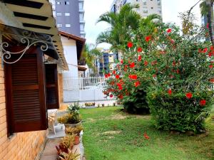 un jardín con flores rojas junto a una casa en Casa ÍSIS de aluguel por temporada em Capão da Canoa com piscina en Capão da Canoa