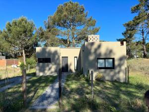 a small white house in a field with trees at Villa Gesell- Av.27 e/100 y 101 in Villa Gesell