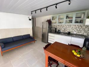 a living room with a blue couch and a kitchen at Chalet de praia in Florianópolis