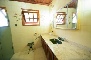 La salle de bains est pourvue d'un lavabo, d'un miroir et d'une douche. dans l'établissement Pousada C Turismo, à Campos do Jordão