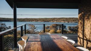a wooden table and chairs on a balcony with a view of the water at Dusk Coffin Bay in Coffin Bay