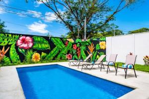 a pool with chairs and a wall with a mural at Casa Emma - Oasis Playa Potrero in Playa Flamingo