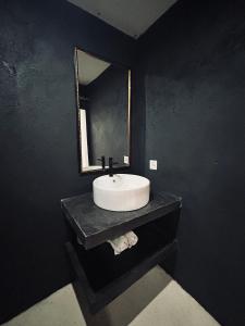 a black bathroom with a sink and a mirror at Surfers Beachfont Kuta in Kuta Lombok