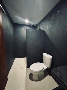 a bathroom with a toilet and a black wall at Surfers Beachfont Kuta in Kuta Lombok