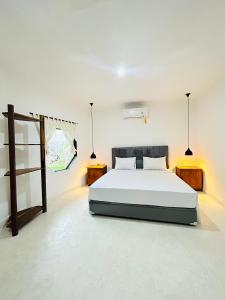 a white bedroom with a bed and two tables at Surfers Beachfont Kuta in Kuta Lombok