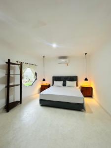 a white bedroom with a bed and two night stands at Surfers Beachfont Kuta in Kuta Lombok