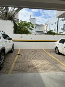 two white cars parked in a parking lot at Apto Praia de Palmas in Governador Celso Ramos
